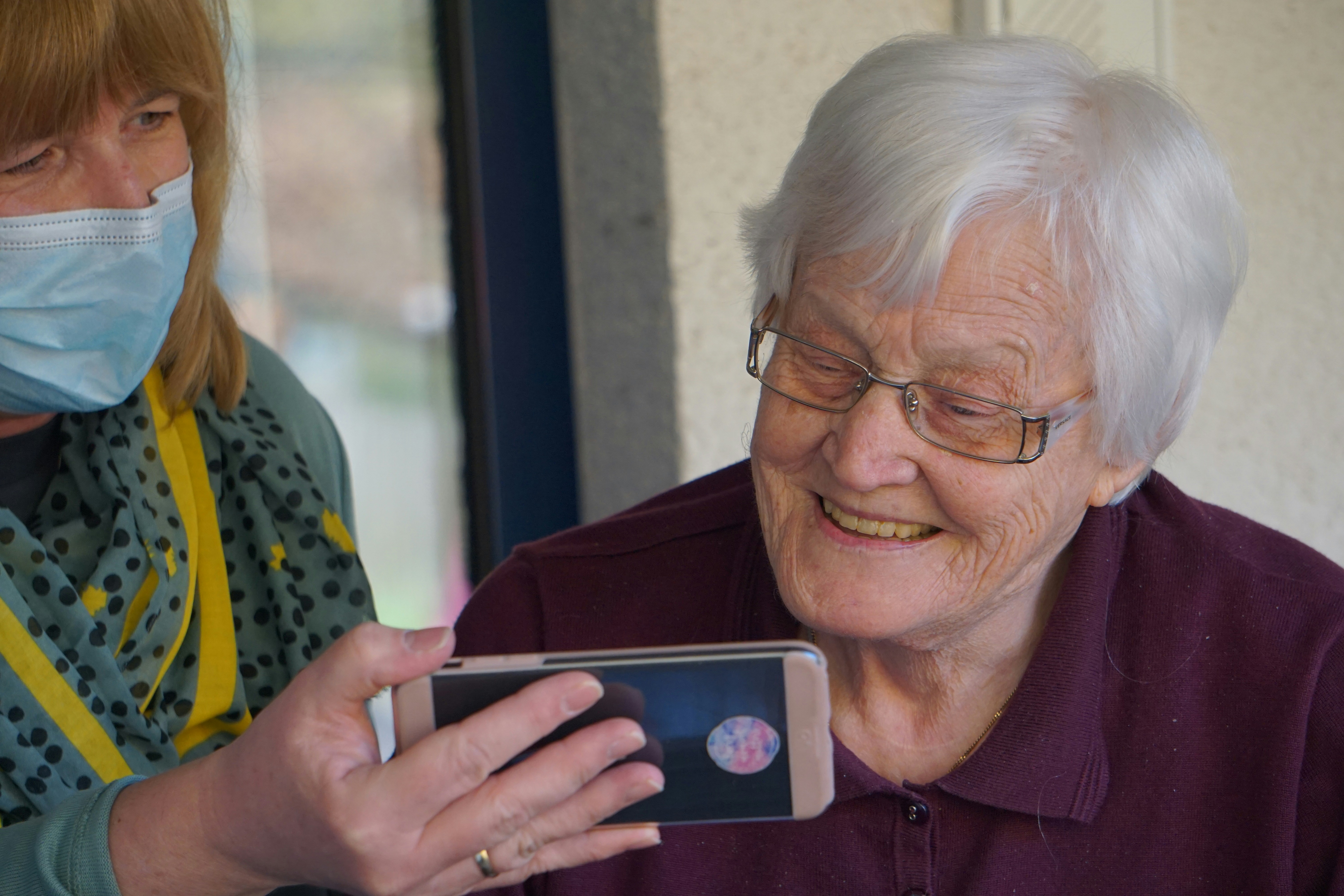 Caregiver chatting and sharing a warm tea time with an elderly client